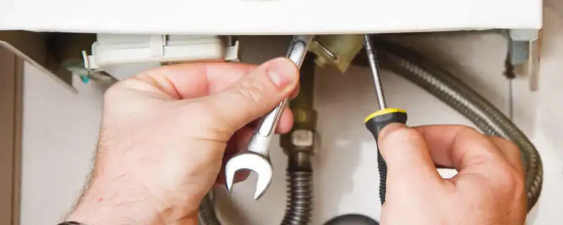 Boiler repair technician tightening pipe fittings and connections in Stockton, CA