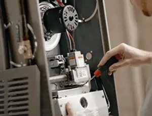 Furnace repair technician inspecting internal components and wiring in Stockton, CA