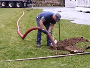 Septic pumping technician servicing a residential septic tank with a vacuum hose in Stockton, CA