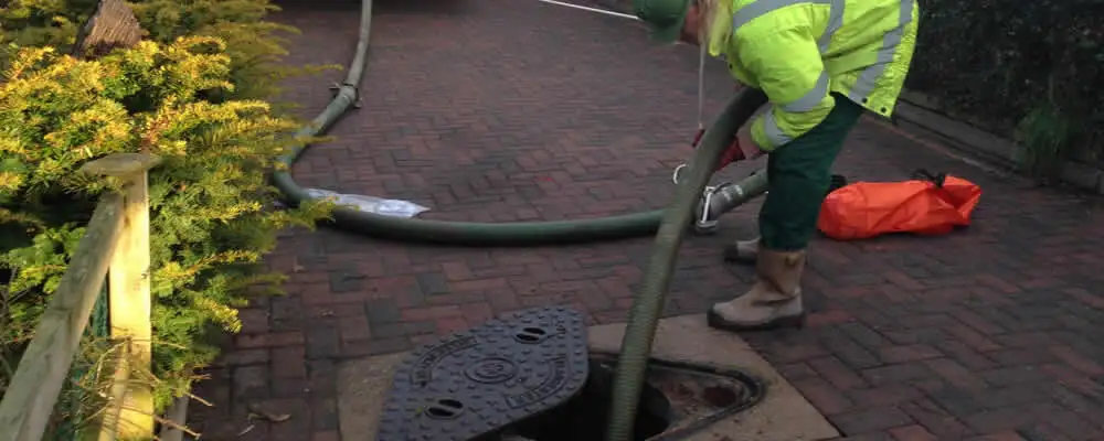 Septic tank cleaning technician servicing a septic tank with a vacuum hose in Stockton, CA