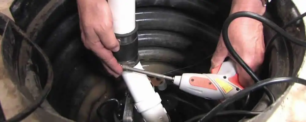 Sump pump installation technician connecting PVC discharge piping in Stockton, CA