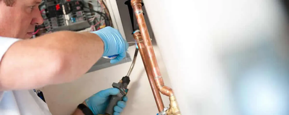 Water heater repair technician testing copper pipe connections and controls in Stockton, CA